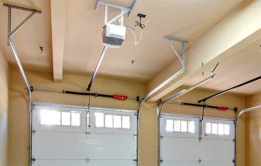 Garage door track and roller assembly mounted along the ceiling rails of a residential garage, the kind of system that keeps a door rolling straight