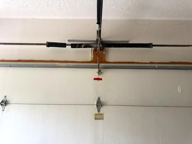 A failed garage door spring, similar to the kind of hardware damage that factors into a panel repair versus replace decision