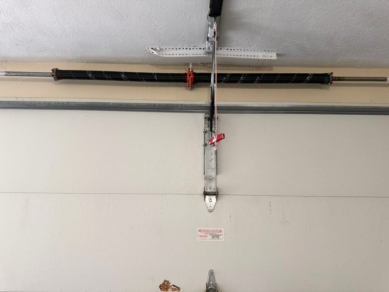 Torsion spring and hardware on a residential garage door, the kind of hardware checked during a seasonal maintenance visit