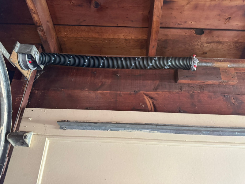 Garage door cable and drum assembly mounted next to the torsion spring on a residential door in Cleveland